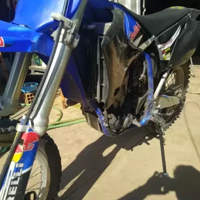 Motociclo de todo-o-terreno azul e preto com logos Red Bull e pneus de cravos