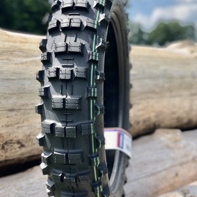 Pneu preto novo para mota com padrões de aderência e linhas verdes colocado em troncos