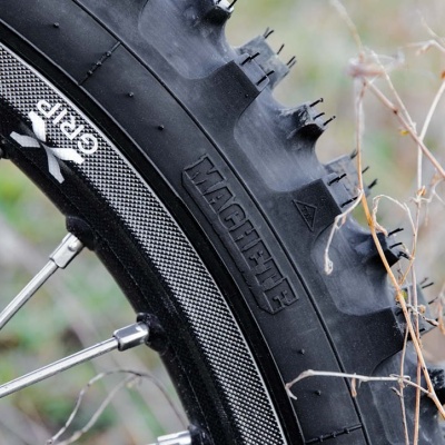 Pneu preto com cravos largos, faixa refletora e textos HACHETTE e SRI5