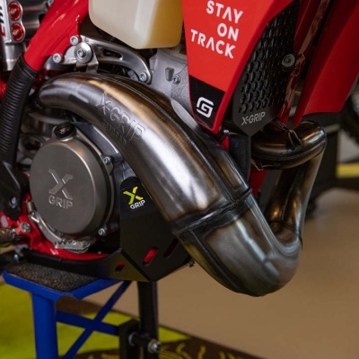 Escape metálico polido de motocicleta com marca X-GRIP montado em moto vermelha