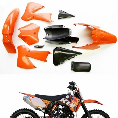 Conjunto de carenagens laranja e preto para mota KTM com mota KTM preta e laranja ao fundo