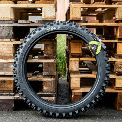 Pneu de bicicleta todo-o-terreno preto com cravos contra paletes de madeira
