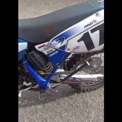 Motocross azul e branco com número 17 e vários textos em painel lateral