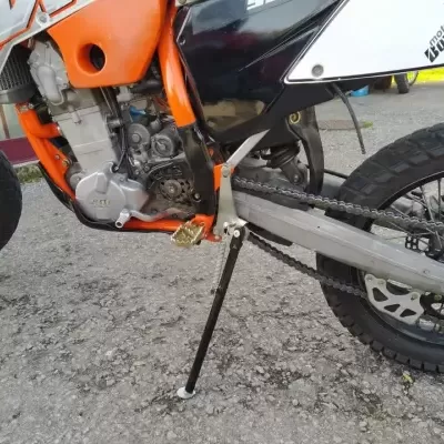 Motocicleta laranja e preta com detalhes visíveis no motor e roda traseira