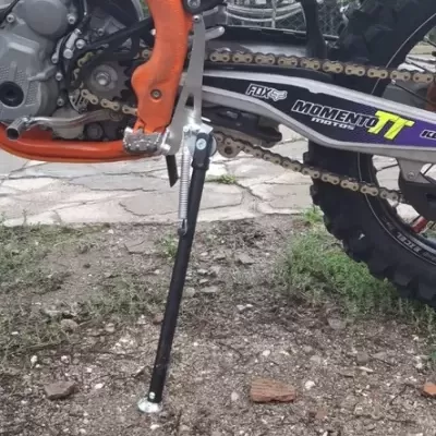 Moto de motocross com quadro laranja, corrente dourada, roda de tacos e número 296.