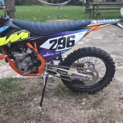 Moto de motocross KTM laranja com banco azul e números 296