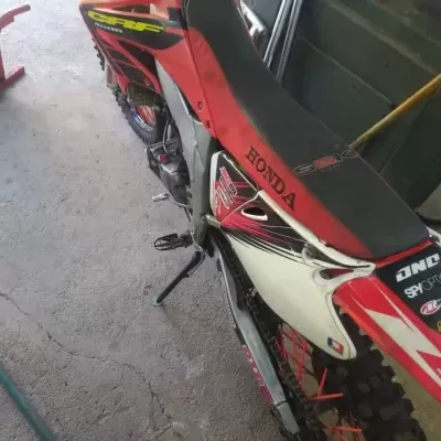 Motocross Honda vermelha e branca com logos em garagem