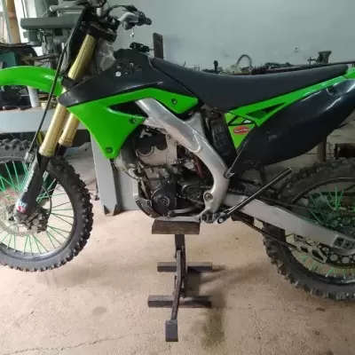 Mota de cross verde e preta em suporte na oficina