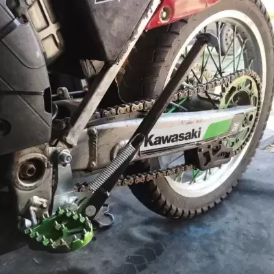 Roda traseira de mota Kawasaki com corrente e apoio de pé verde