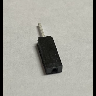 Conector pequeno preto com haste metálica sobre fundo branco