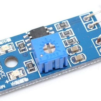 Placa eletrónica azul com potenciômetro e sensor preto cilíndrico