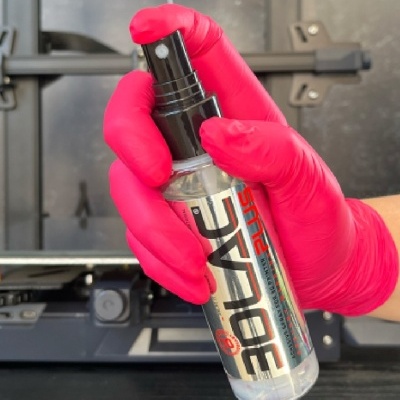 Spray SPY RC PLUS em garrafa transparente com tampa preta sendo segurada por mão com luva rosa