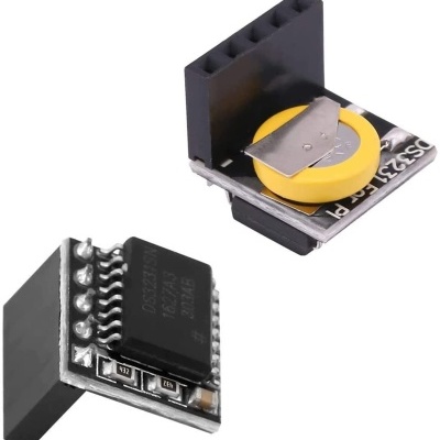 Dois componentes eletrónicos pequenos, um com bateria tipo moeda amarela e placa preta