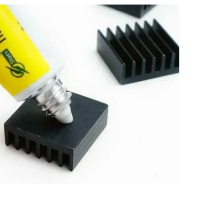 Tubo amarelo de cola a aplicar em dissipador de calor preto quadrado com aletas.