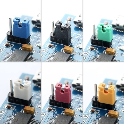 Componentes eletrónicos jumpers coloridos numa placa de circuito azul