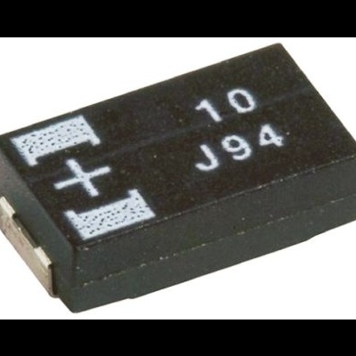 Componente eletrónico preto com marcações e símbolos de polaridade