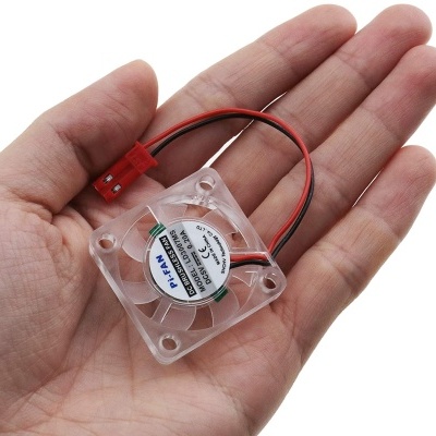 Ventoinha pequena quadrada de plástico transparente com fios e conector vermelho na palma da mão.