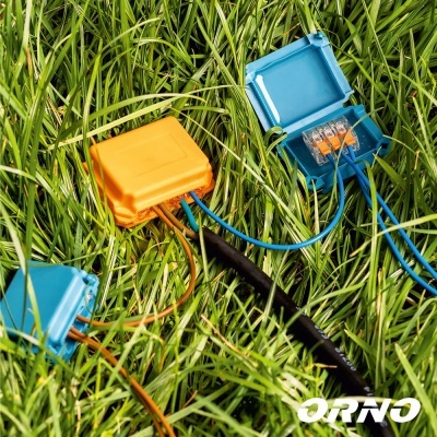 Caixas de conexões elétricas coloridas na relva com fios conectados e logo ORNO