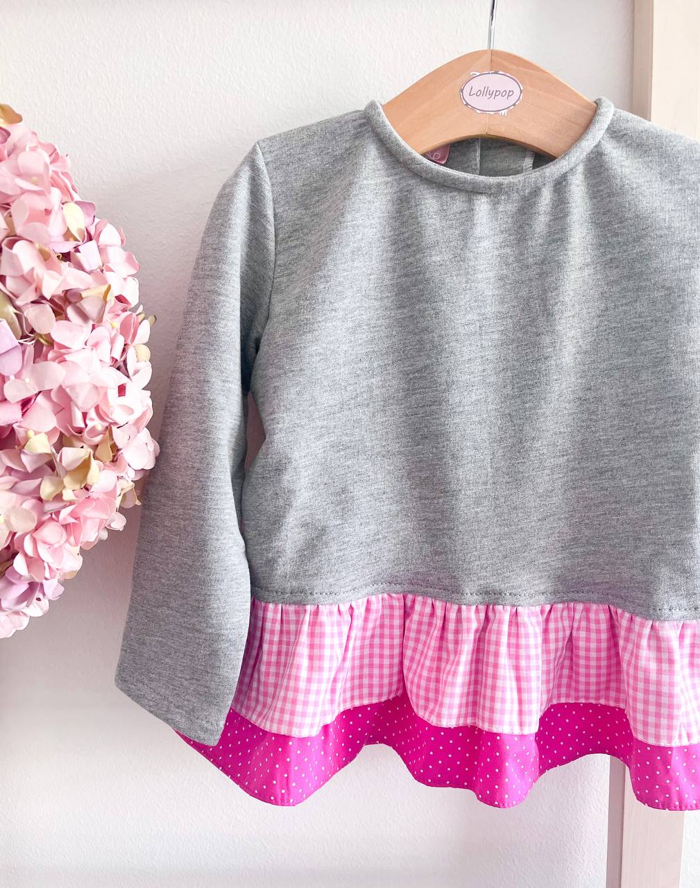 Camisola cinza com barra rosa e cabide de madeira