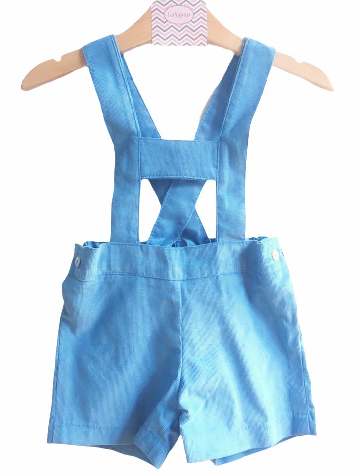 Macacão curto azul para bebé com alças cruzadas em cabide de madeira