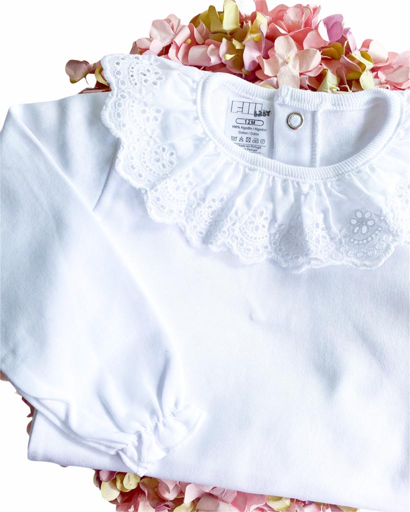 Camisola branca de bebé com gola rendada sobre flores artificiais