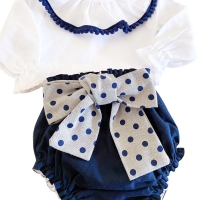 Roupa de bebé com body branco e calções azuis com laço cinza às bolinhas