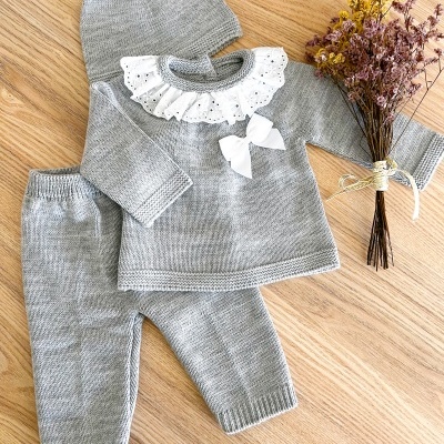 Conjunto de roupa de bebé cinzenta em malha com gola branca rendada e laço, com gorro e flores secas