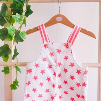 Macacão infantil branco com estrelas rosa e tiras rosa às riscas