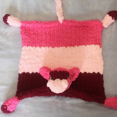 Tecido quadrado em tricô com cores rosa, rosa claro e bordô e rosto de animal no centro