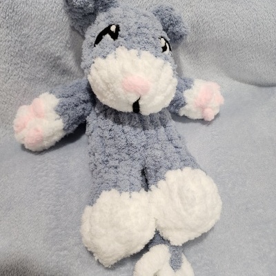 Peluche cinza e branco com detalhes rosa sobre tecido cinza claro