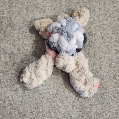 Brinquedo em peluche de pompons coloridos sobre tecido cinzento