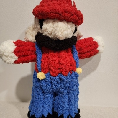 Boneco croché personagem com chapéu vermelho e roupa colorida