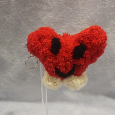 Peluche coração vermelho com olhos e boca pretos e chaveiro dourado