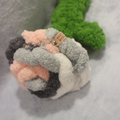 Pelúcia em forma de flor colorida com etiqueta HAND MADE num fundo cinzento