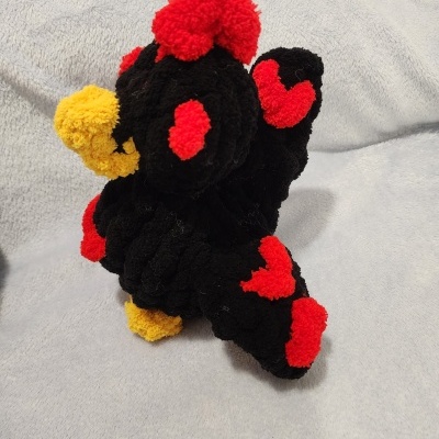 Pelúcia de ave preta com detalhes vermelhos e amarelos