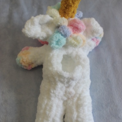 Fantasia em pelúcia branca com detalhes coloridos e apêndices amarelo e azul