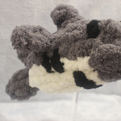 Boneco de peluche cinzento, branco e preto com textura felpuda