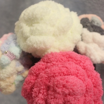 Flores decorativas felpudas em branco, rosa e cores pastel sobre fundo cinzento