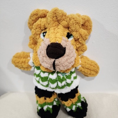 Ursinho de peluche amigurumi colorido com roupa verde e branca