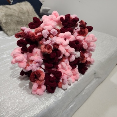 Almofada pompom em tons de rosa e vermelho sobre sofá cinza claro