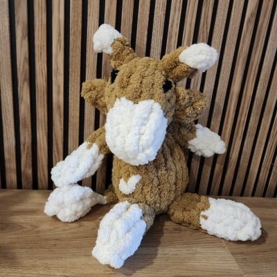 Peluche castanho e branco de girafa sentado sobre madeira com painéis de madeira ao fundo