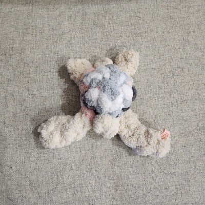 Brinquedo de pelúcia felpudo creme com detalhes em cinza, branco e rosa
