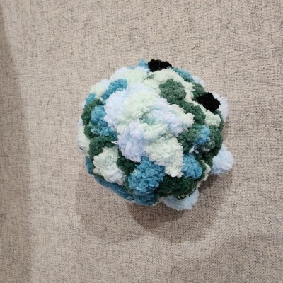 Bola artesanal de pompons de lã coloridos sobre tecido cinza claro
