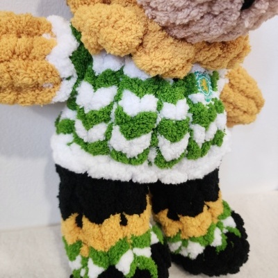 Boneco felpudo colorido em verde, branco, preto e amarelo, com textura macia