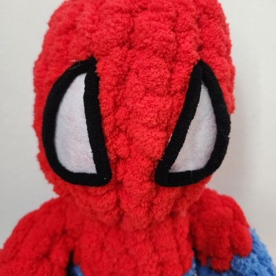 Boneco de peluche vermelho e azul com olhos grandes brancos e contorno preto