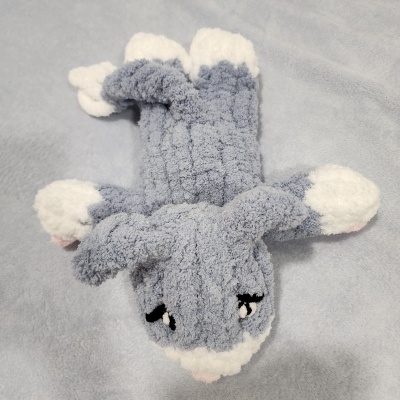 Boneco de peluche em forma de tubarão cinzento e branco sobre tecido cinzento