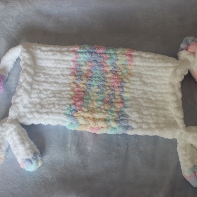 Tapete felpudo branco com padrão colorido e extremidades em várias cores pastel sobre fundo cinza