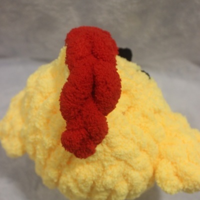 Peluche amarelo de frango com crista vermelha visto de cima