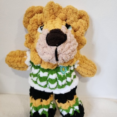 Peluche leão com roupa verde, branca, preta e amarela e emblema Sporting Portugal