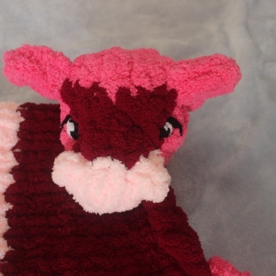 Pelúcia rosa e roxa de tecido fofo com olhos bordados.